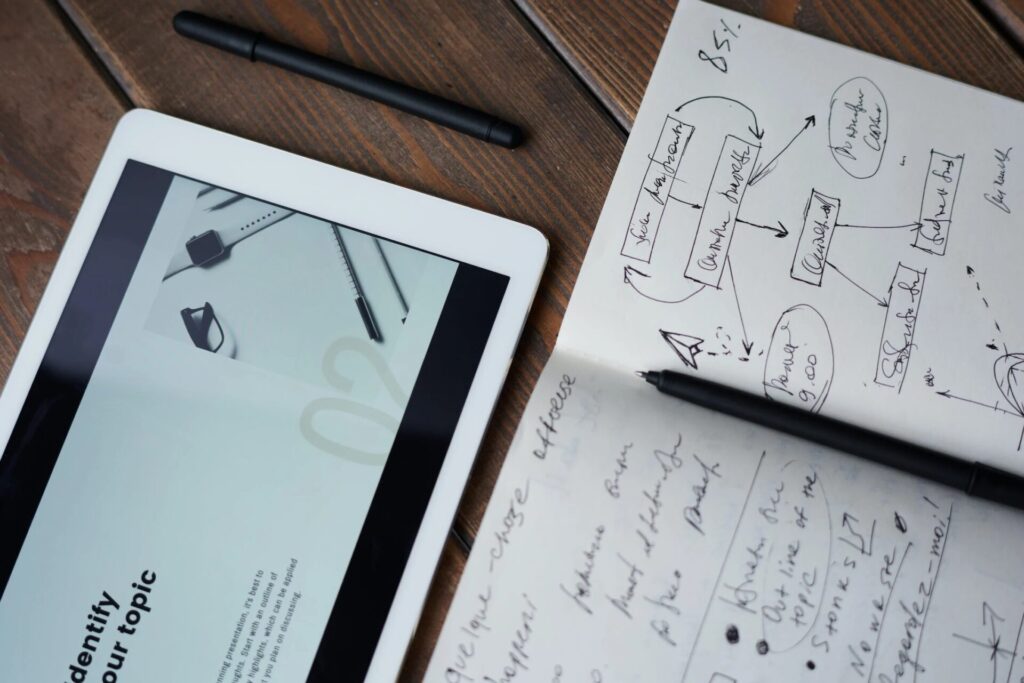A close-up of notes on a notebook beside a tablet.